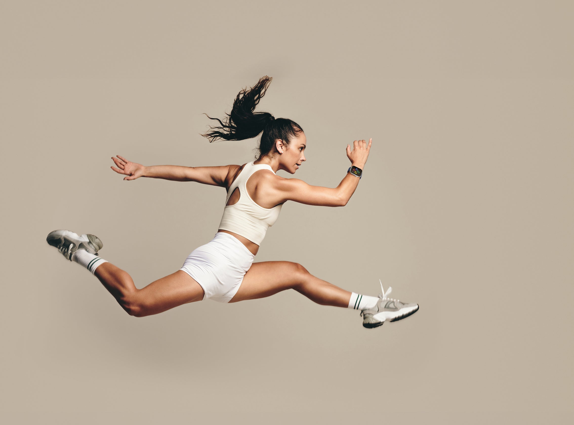 Woman in athletic wear jumping in the air against a plain background wearing air 5 pro