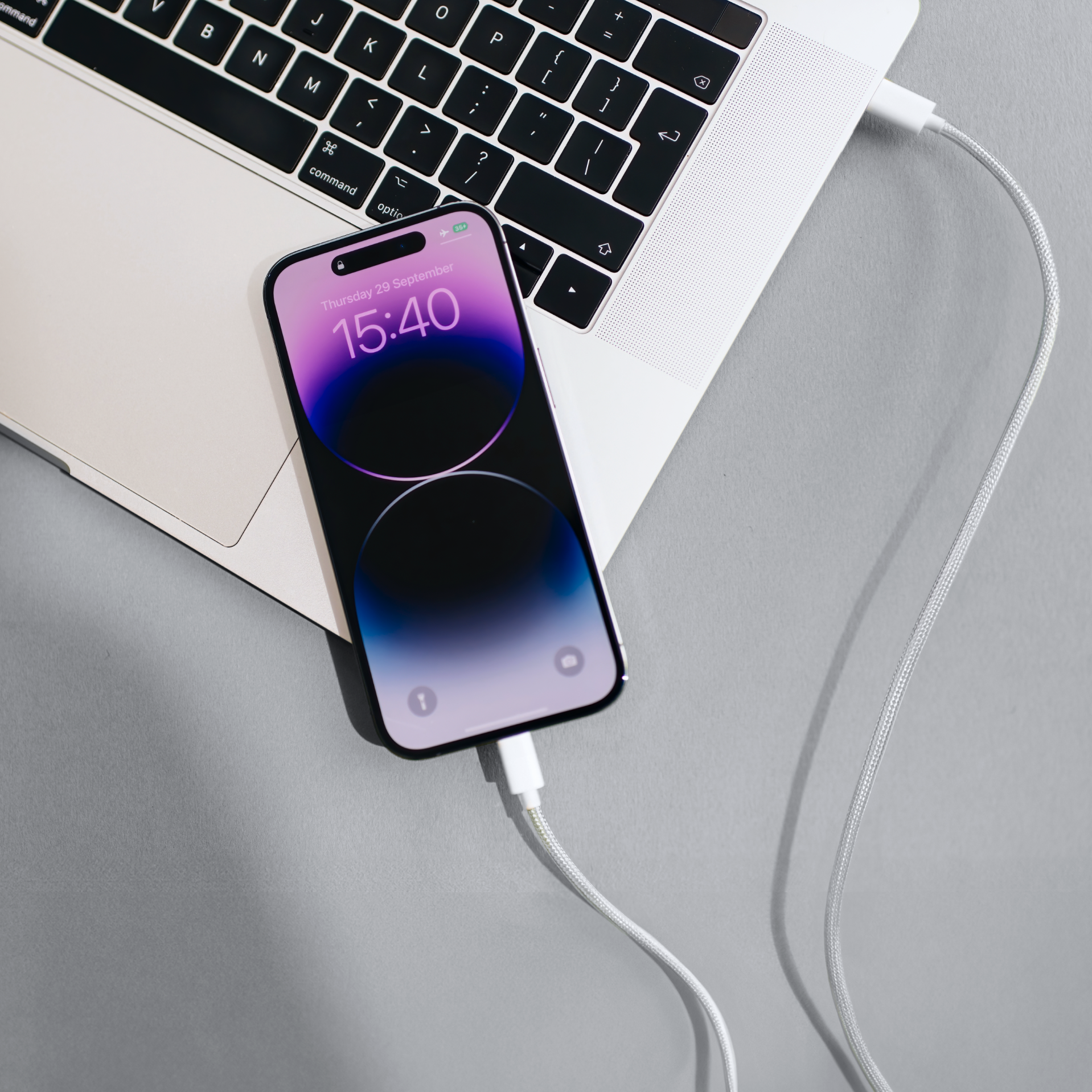 Smartphone charging on a desk with a laptop in the background